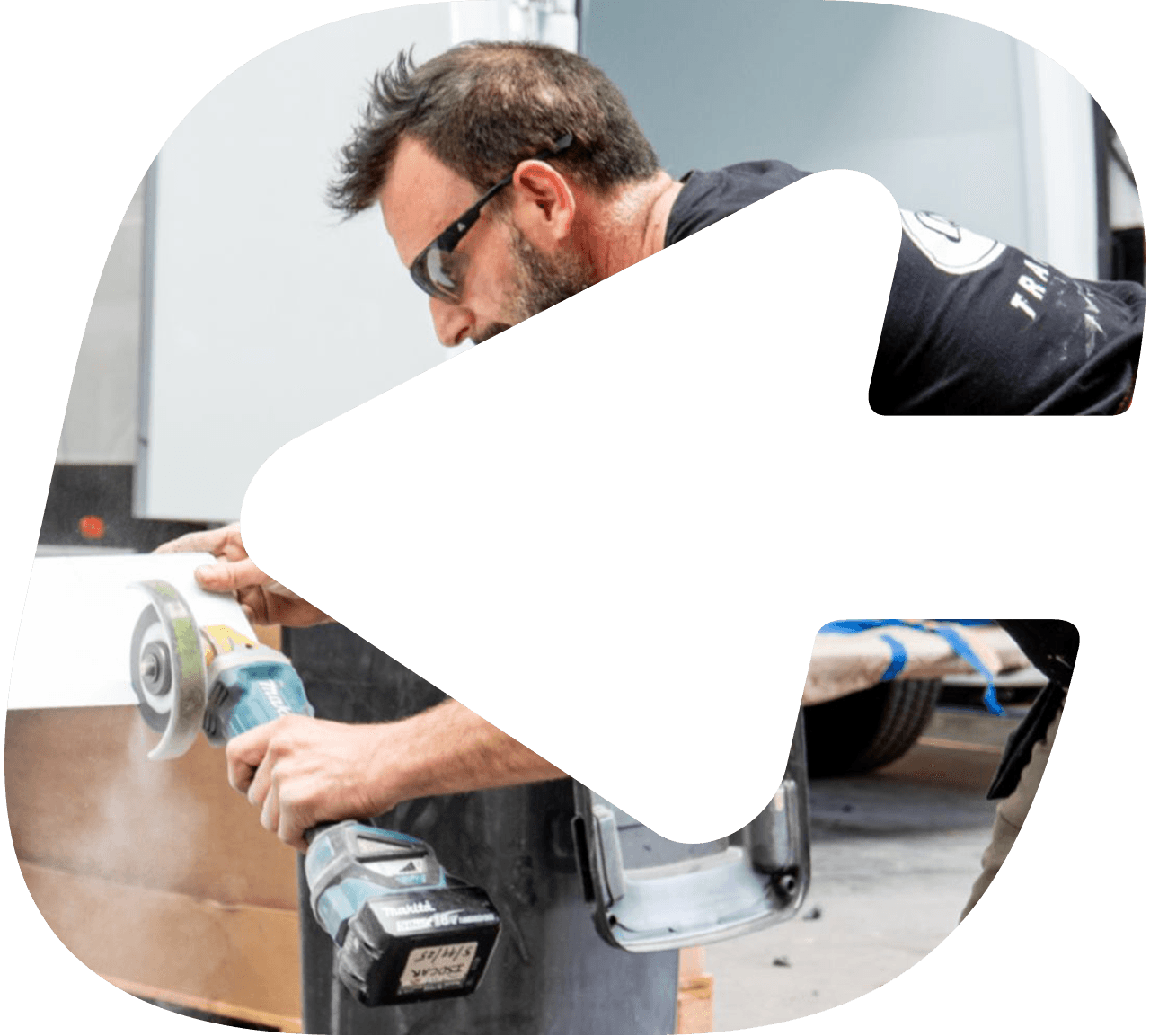 An Isocar body builder cutting an insulated panel to size with an angle grinder