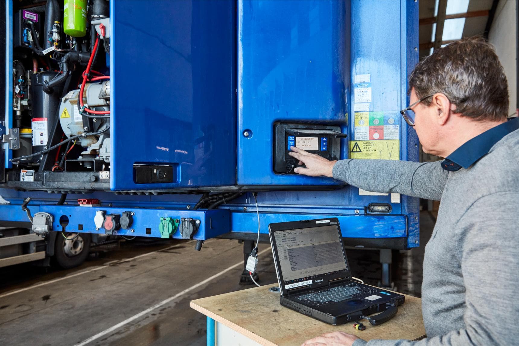 A service engineer reading out a blue semi-trailer's Carrier unit on a laptop